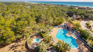 An aerial view of a resort with a large swimming pool, lounge chairs, and a view of the ocean. - Deja Blue, Gulf Views, Condo at Tops'l, Pool (Miramar Beach)