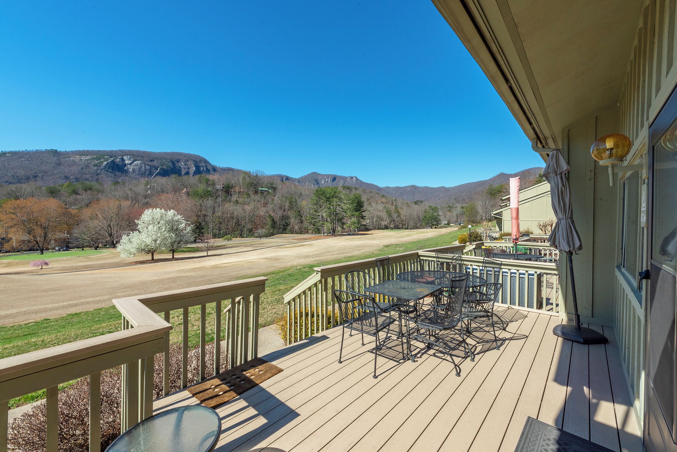 Une terrasse dotée de mobilier d’extérieur, offrant une vue sur une chaîne de montagnes et un ciel dégagé.