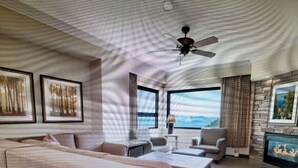 A spacious living room with a large sofa, a coffee table, and a television. There are large windows providing a view of the outdoors. - Experience Tahoe's Ski Scene at Holiday Inn Club Vacations Tahoe Ridge Resort (Stateline)