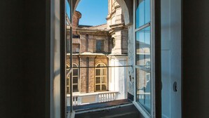 Un balcon offrant une vue sur un bâtiment historique doté d’arcatures et d’un toit recouvert de tuiles.