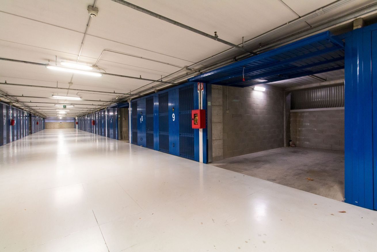 A long, empty corridor with blue doors numbered 9 and 10, and a red emergency exit sign.