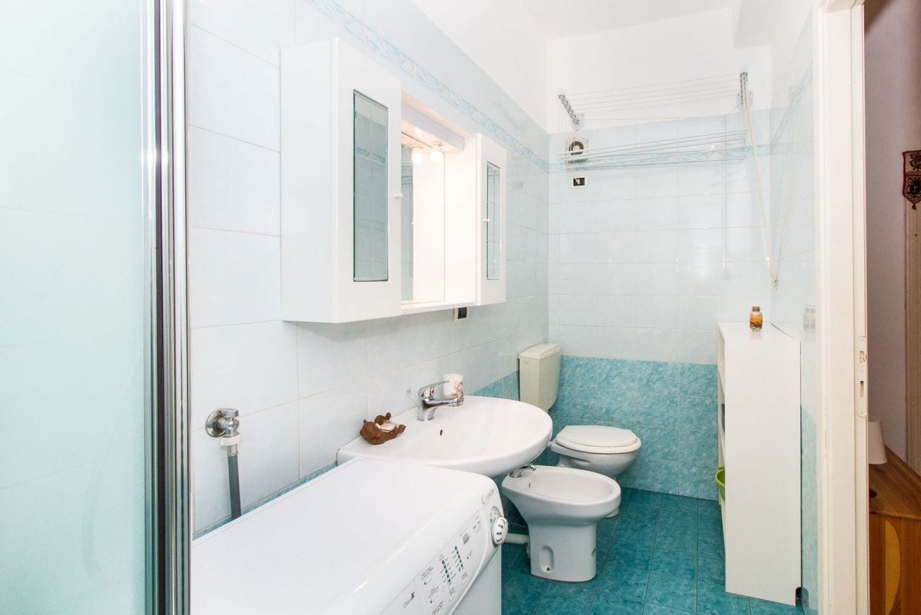 A bathroom with a glass shower enclosure, two sinks, a toilet, and a cabinet.