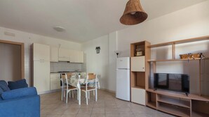 A compact living space with a kitchenette, dining area, and a TV on a wooden stand.