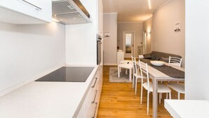 A modern kitchen with white cabinetry, a black induction cooktop, and a built-in range hood. - MM Pozzo Strada Terrace Apartment (Turin)