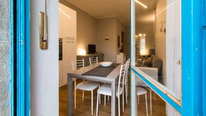 A modern kitchen with white cabinets, a dining table with chairs, and a large window. - MM Pozzo Strada Terrace Apartment (Turin)