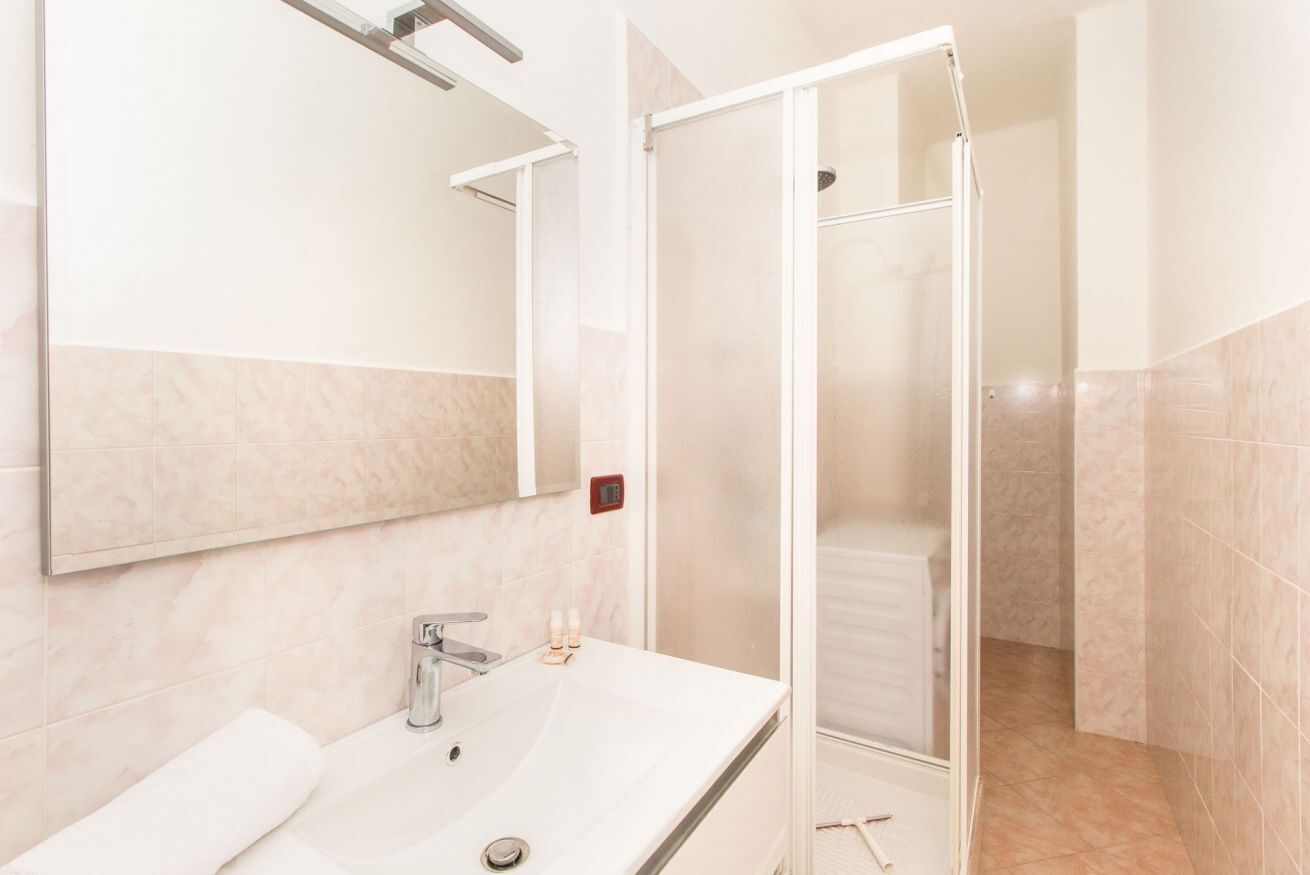 A bathroom with a sink, mirror, and shower.