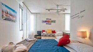 A hotel room with a bed, a desk, a TV, and a wall with artwork. - Porta Nuova & Valentino Apartment (Turin)