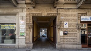 Une rue étroite avec une entrée d’immeuble, une pancarte indiquant une vente privée et un panneau interdisant le stationnement.