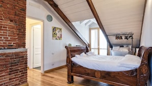 Une chambre avec un lit en bois, un mur en briques et un plafond en pente.