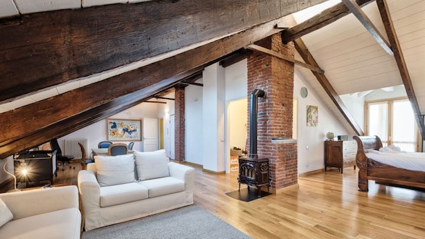 Une chambre à coucher de style loft avec des poutres apparentes, une cheminée en briques, un lit et un canapé.