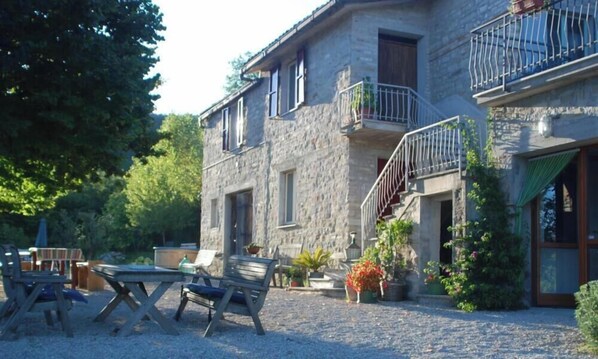 A stone building with a balcony, outdoor seating, and potted plants. - A beautiful agritourism property with breathtaking views of the vineyards and mountains. Francesco. (Marche)