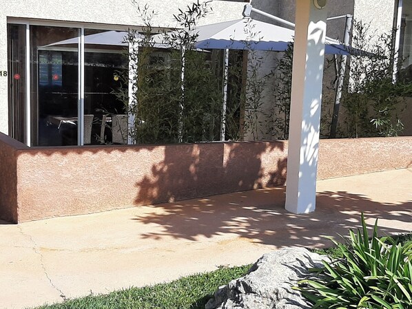 Ein Gebäude mit Glasfassade, Sitzbereich im Freien mit Sonnenschirmen und einer Steinmauer.