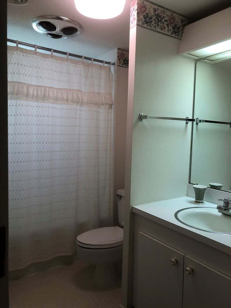 A bathroom with a toilet, a sink, a mirror, and a shower curtain.