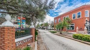 A street view with a brick building labeled 'DUNEDIN' and a red brick building with 'MAIN STREET' signage. -  5 star condo on Main Street! (Dunedin)