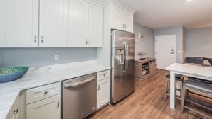 A modern kitchen with white cabinets, stainless steel appliances, and a marble countertop. -  5 star condo on Main Street! (Dunedin)