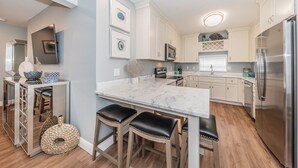 A modern kitchen with white cabinets, a marble countertop, and stainless steel appliances. -  5 star condo on Main Street! (Dunedin)
