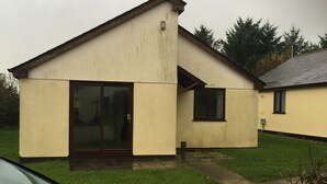 A single-story building with a flat roof, large sliding glass doors, and a small attached garage. - Lovely 3 Bedroom Holiday Bungalow Near Bude (Bude)