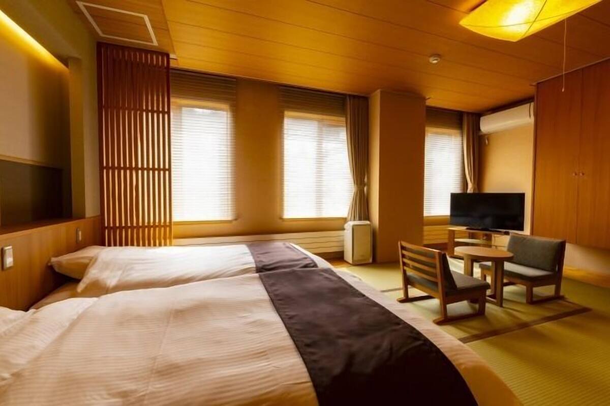 Een hotelkamer met twee bedden, een televisie, een klein tafeltje en een stoel.