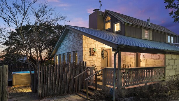 A stone house with a metal roof, a wooden fence, and a hot tub in the backyard. - 1800 ’s Home at Lost Creek/Hot Tub/Close to Downtown/Bluebonnet (Fredericksburg)