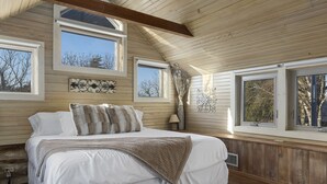 A bedroom with a large bed, wooden ceiling beams, multiple windows, and a view of trees. - 1800’s Home at Lost Creek/Hot Tub/Close to Downtown/Bluebonnet (Fredericksburg)