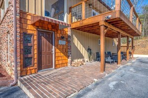 Un bâtiment en bois à deux étages, doté d’une façade en briques, d’un porche en bois avec des sièges extérieurs et surplombant un ciel dégagé.