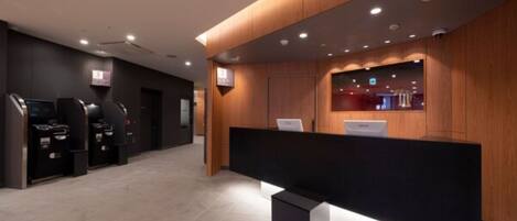 Check-in and unwind in our welcoming reception area, featuring a central desk, self-service kiosks, and a large flat-screen TV.