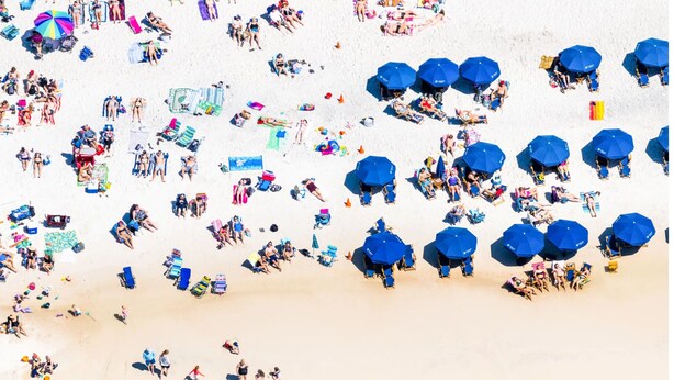 Vista aérea de una playa con gente, sombrillas y sillas de playa.