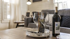 Una mesa con una botella de vino, dos copas de vino y un sacacorchos sobre un encaje.