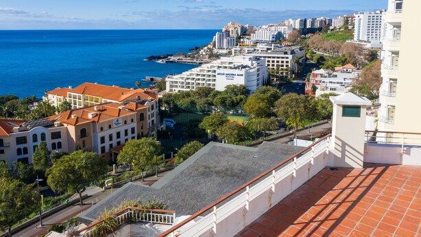 A coastal cityscape with buildings, a beach, and a clear blue sky.