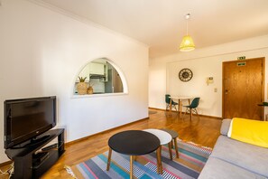 Ein Wohnzimmer mit Fernseher, einem runden Tisch, einer Couch und Holzboden.