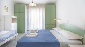 A bedroom with a bed, a wardrobe, a nightstand, and a hanging light fixture.