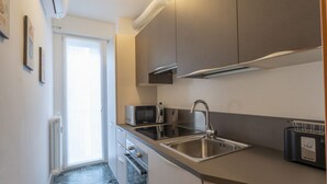 Een compacte keuken met een magnetron, spoelbak en broodrooster, met een modern design en een raam voor natuurlijk licht.