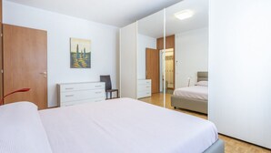 Een slaapkamer met een groot bed, een kledingkast, een bureau en een stoel.
