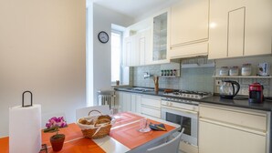 A compact kitchen with white cabinets, a gas stove, and a coffee maker. - Zia Dina Apartment (Pasian di Prato)