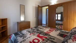 A bedroom with a bed, a wardrobe, a mirror, and a door leading to another room. - Leisure & Business (Buttrio)