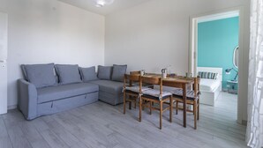 Una sala de estar moderna con un sofá gris, una mesa de comedor de madera y sillas.