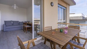 Un balcón con mesa, sillas y sofá de madera.