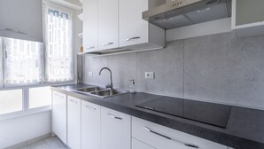 Una cocina moderna con armarios blancos, encimera negra y pileta de acero inoxidable.