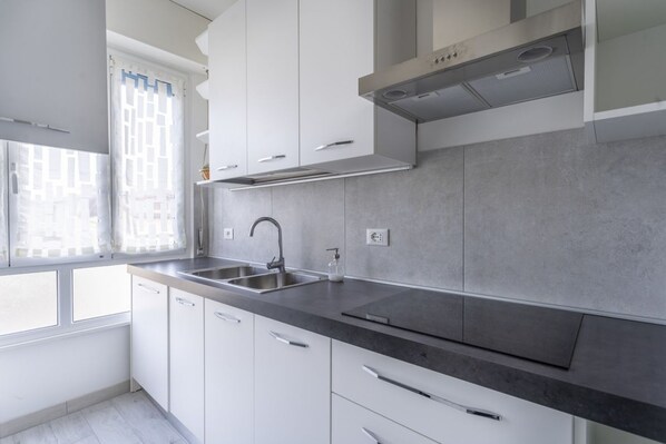 Una cocina moderna con armarios blancos, encimera negra y pileta de acero inoxidable.