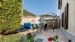 A patio with outdoor seating, a pool, and a stone building in the background. - Borgo Santa Lucia Apartment with Private Parking & Garden (Gubbio)