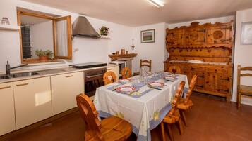 A kitchen with a dining table set for four, wooden cabinets, a stove, and a large wooden cabinet with intricate designs.