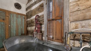 Un baño rústico con una bañera grande, paredes de madera y un grifo antiguo.