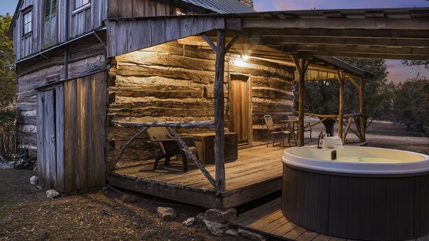 Una cabaña rústica con jacuzzi y zona de estar exterior.
