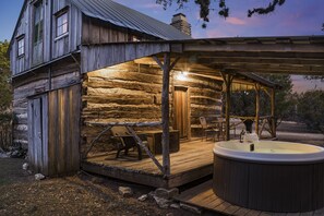 Una cabaña rústica con jacuzzi y zona de estar exterior.