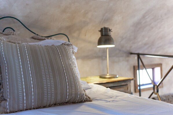 Un dormitorio acogedor con cama, lámpara y ventana.