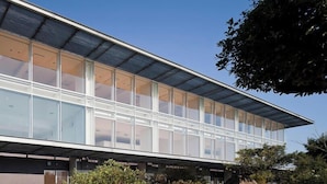 Een modern gebouw met een plat dak, grote glasramen en een metalen luifel.