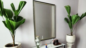 A bathroom with a white marble vanity, a large mirror, and two potted plants.