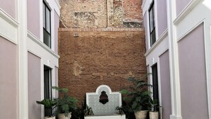 A courtyard with a brick wall, potted plants, and a white bench.