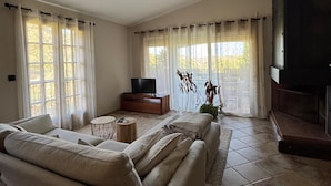 Un salon avec un canapé, un téléviseur posé sur un meuble en bois et une cheminée.