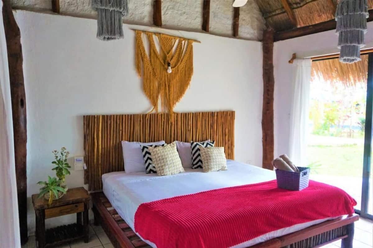 Un lit avec une couverture rouge, une tête de lit en bois et des oreillers à motifs.